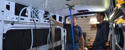 Two individuals stand inside the Supervan as it is being built out